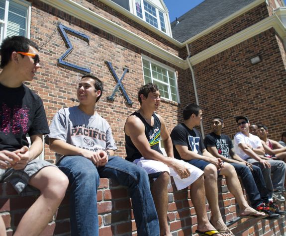 fraternity members hanging out in front of house